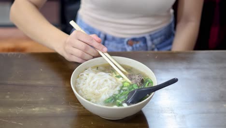 person enjoying vietnamese pho with chopsticks