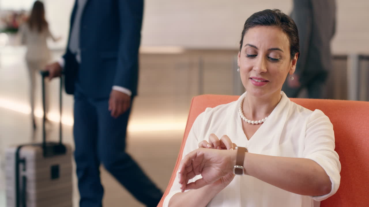 mujer de negocios de raza mixta usando reloj inteligente en el vestíbulo de negocios