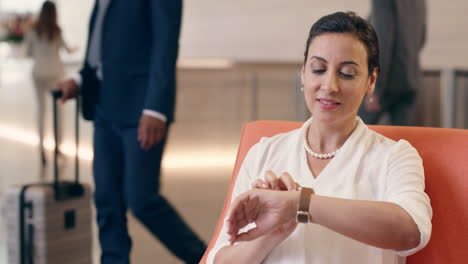 Mixed-Race-businesswoman-using-smart-watch--in-business-lobby