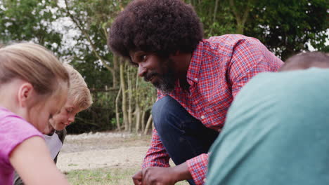 team leader showing group of children on outdoor camping trip how to make fire