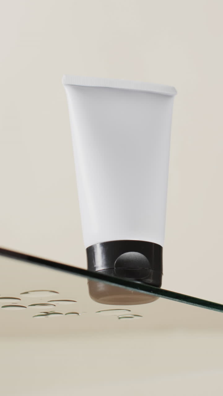 video vertical de un tubo de producto de belleza en un estante de vidrio con espacio de copia en un fondo blanco