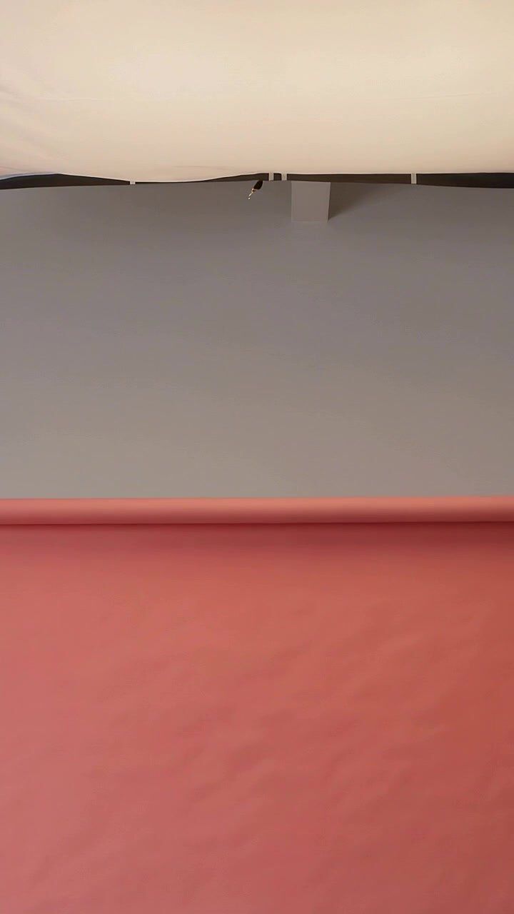 Vertical video: Rotating roller swapping backdrop from teal to pink at studio ceiling with clip