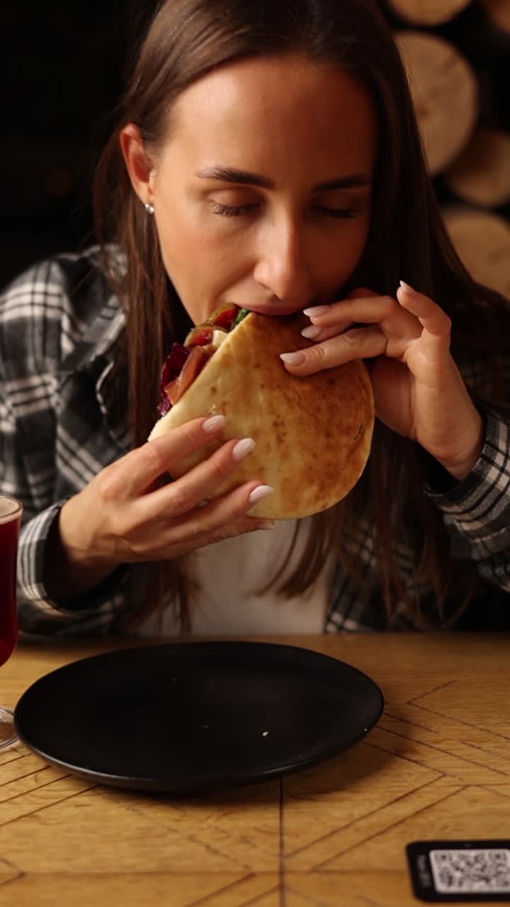 mujer comiendo sándwich de pita en un restaurante