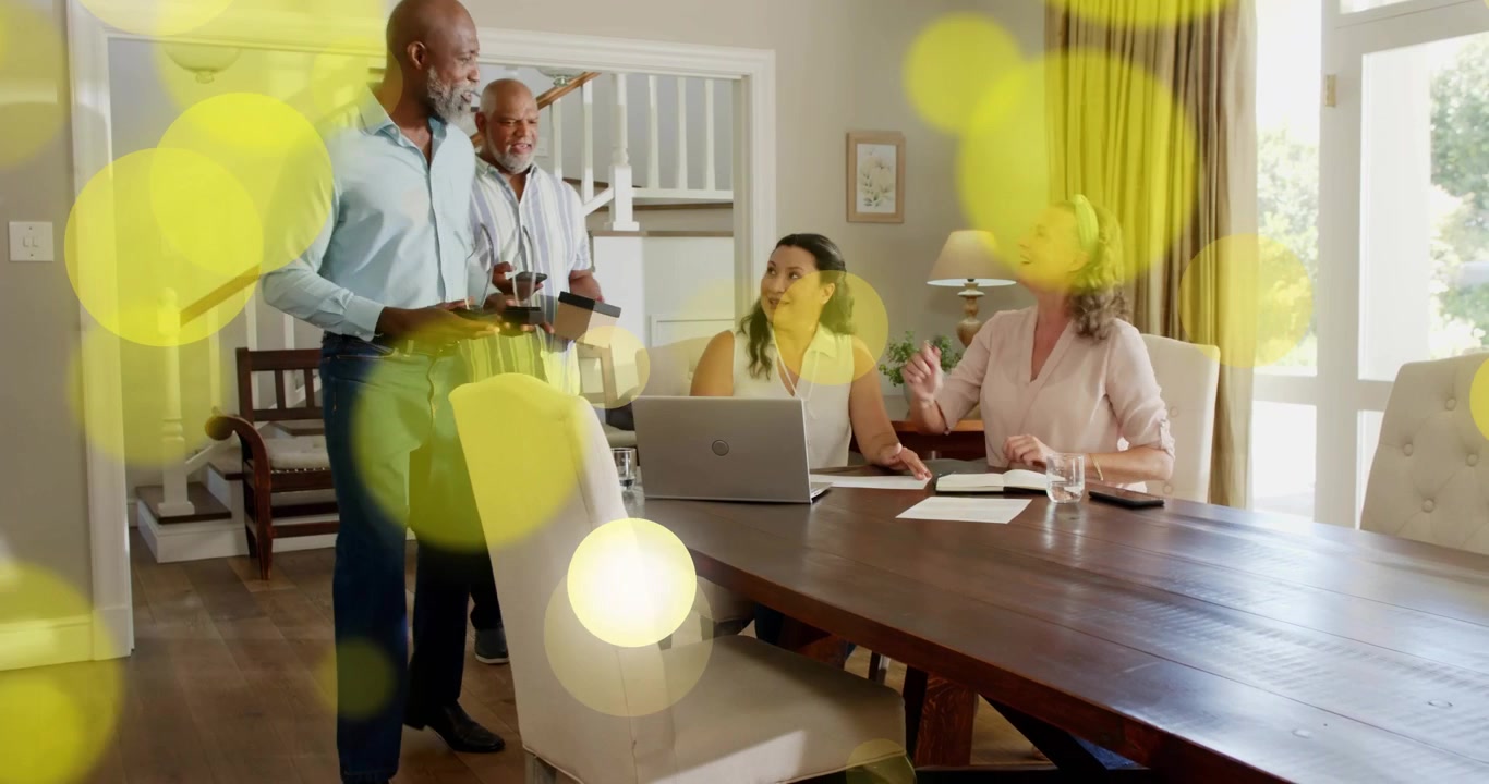 Women reading papers on table when man coming placing device starting tech demo with yellow bokeh