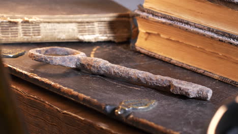 magical ancient key and historical books on the table in changing light