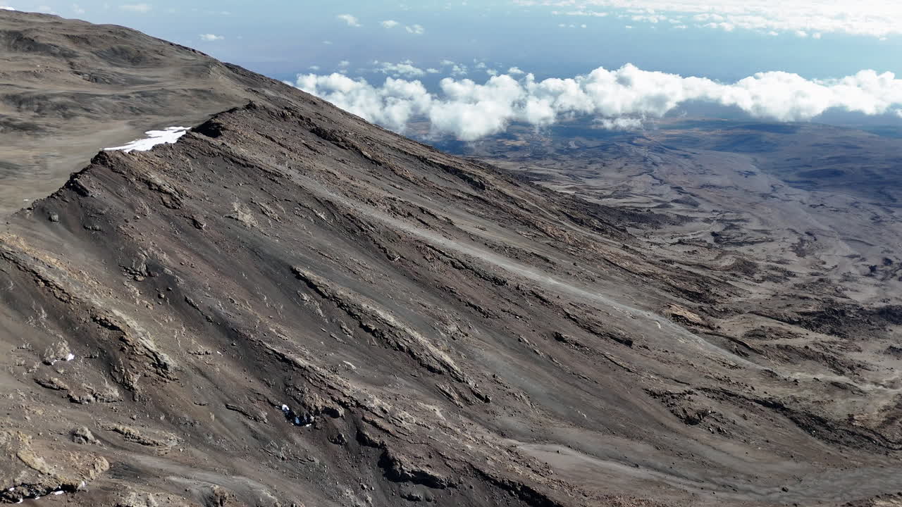 una vista cinematográfica aérea del icónico pico uhuru en la cima del monte kilimanjaro, revelando lentamente la toma de un avión no tripulado.