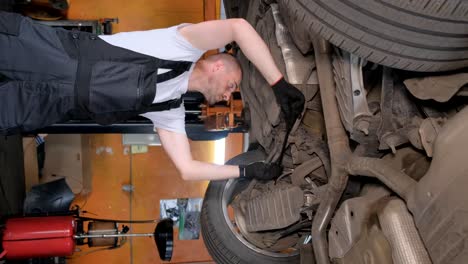 mechanic working on the underside of a car in a garage