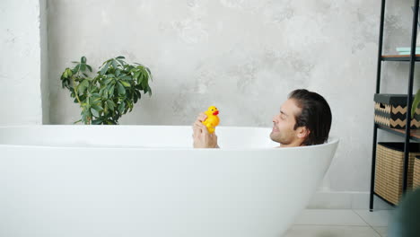man relaxing in a bathtub with a rubber duck