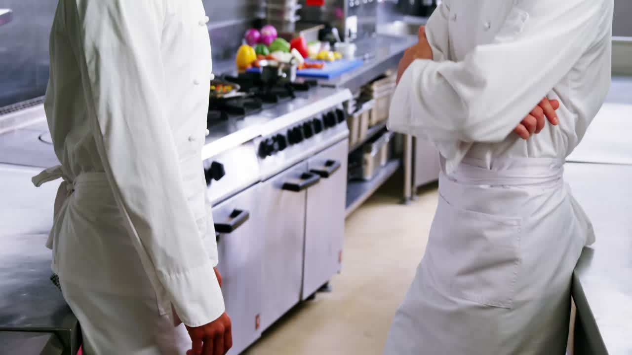 dos cocineros interactuando entre sí en la cocina comercial