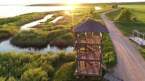 girl climbing staircase in wetland birding hide observation tower to watch golden sunrise aerial shot