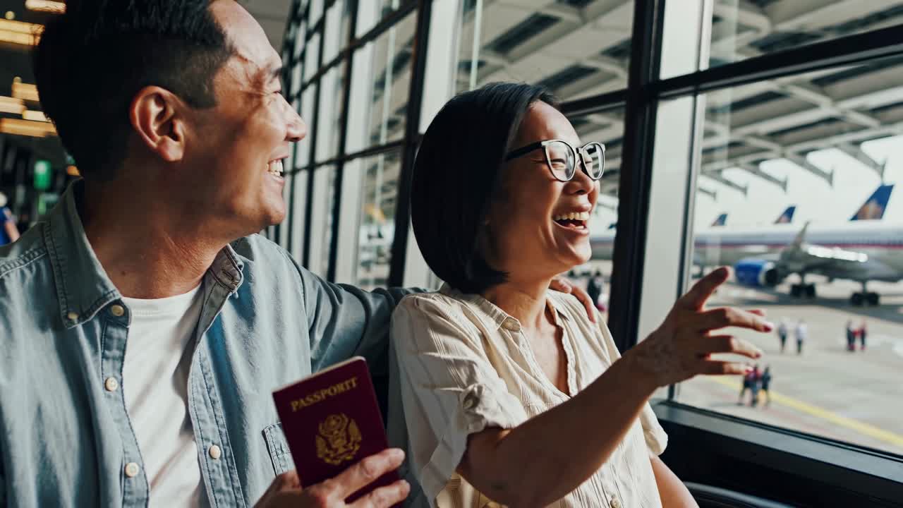 A couple at an airport window, holding a passport, gazes at planes