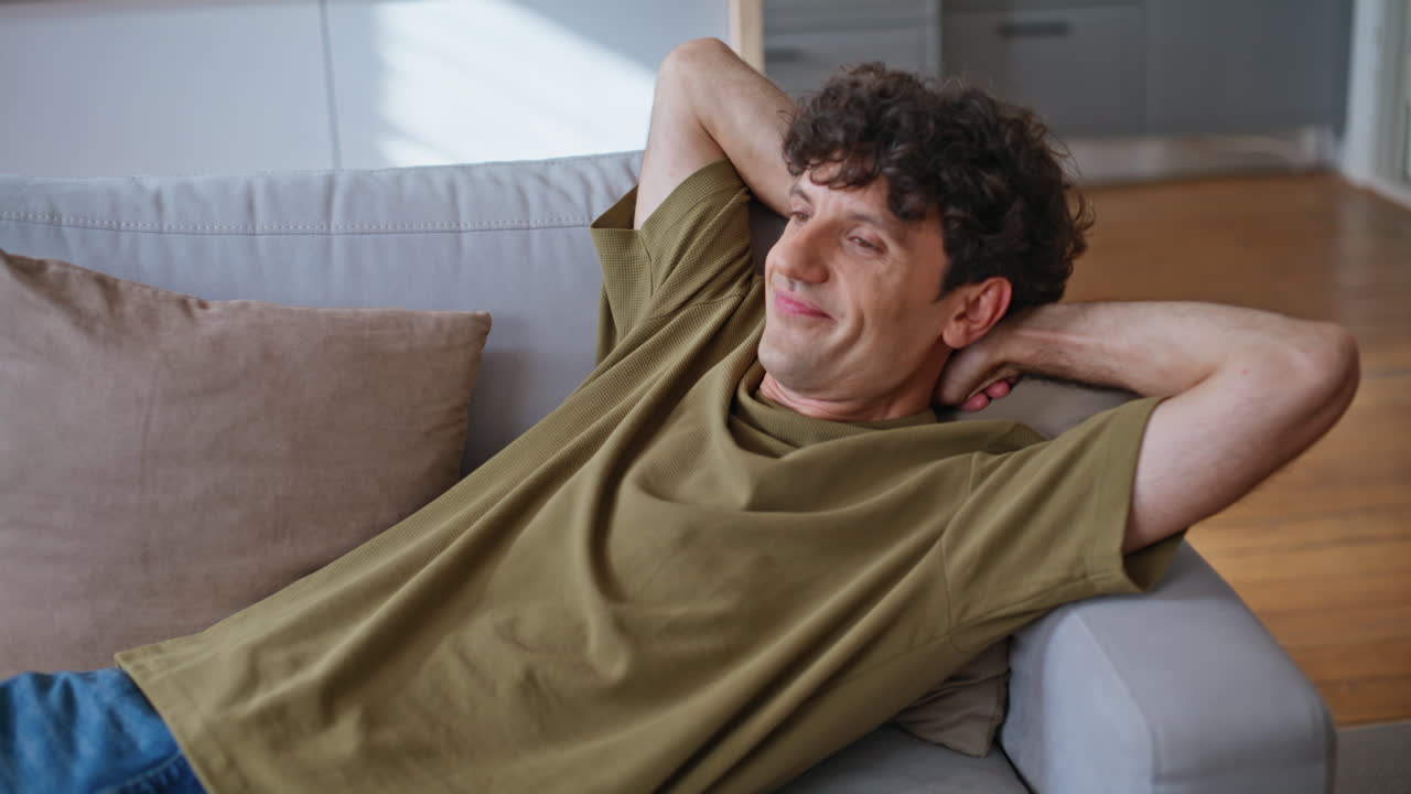 Closeup guy falling couch feeling happy at home. Lazy man taking rest chilling