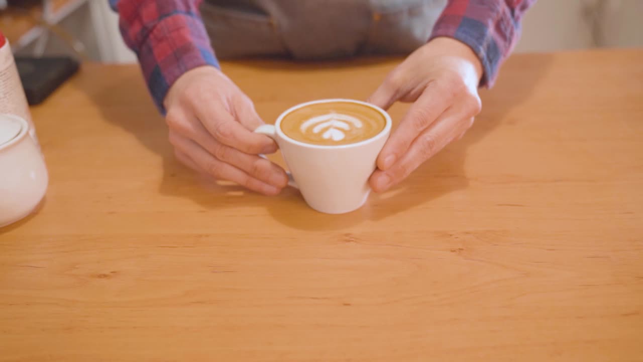 바리스타는 라테 아트와 함께 커피 컵을 카운터에 놓습니다.