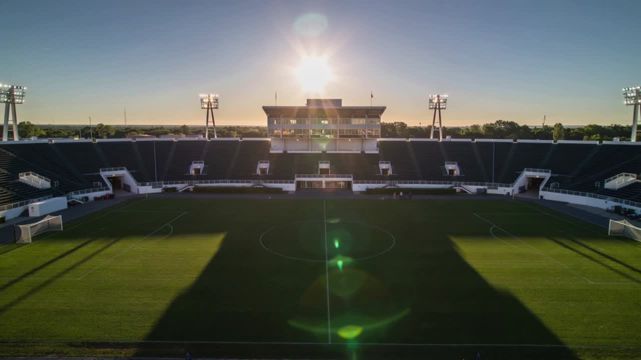 Video verticale: Sole basso e splendente che irradia sulla tribuna centrale e sulle porte mentre la telecamera regola l'esposizione.