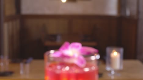 View-inside-Japanese-sushi-restaurant-of-wall-art-with-tilt-down-to-red-cocktail-with-flower-garnish