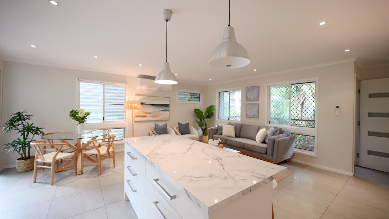 Push past wall to reveal interior kitchen island and open air living room in tropical modern home