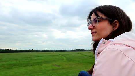 Mujer-Joven-Con-Gafas-Mirando-Un-Vasto-Campo-De-Hierba-Verde-En-Phoenix-Park,-Dublín