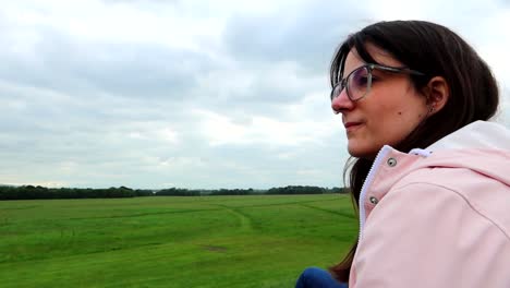 joven con gafas mirando un vasto campo de hierba verde en el parque phoenix, dublín