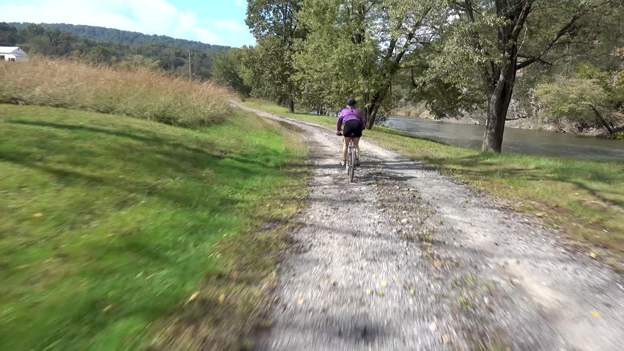 앞에는 여자가 있고 뒤에는 강이 있는 커브길을 빠르게 돌고 있습니다.