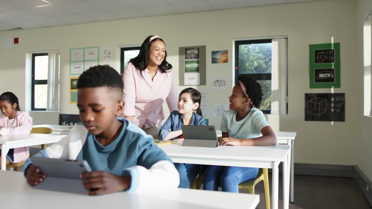 Insegnante afroamericano che guida i bambini in classe dopo aver visto un problema con il tablet, bambino in primo piano al lavoro