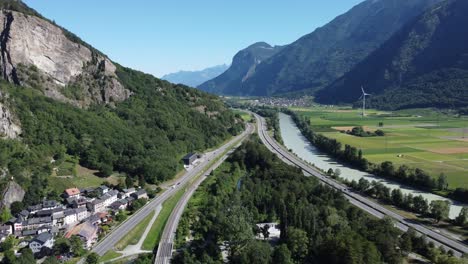 Vista-De-Drones-A-Través-Del-Valle-En-Valais-Con-Una-Autopista,-Una-Autopista,-El-Río-&quot;rhone&quot;-Y-Un-Pequeño-Pueblo