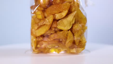a clear container filled with freeze-dried quince pieces, highlighting their golden-yellow hue and natural texture. perfect for snacking or adding to recipes.