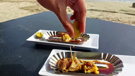 hand squeezing calamansi juice over pork siomai, a traditional filipino snack while enjoying the sunny weather at the beach