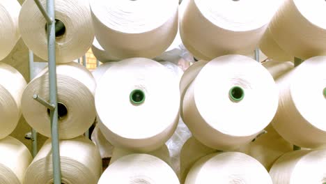 rolls of white cotton on a rack at a cotton mill