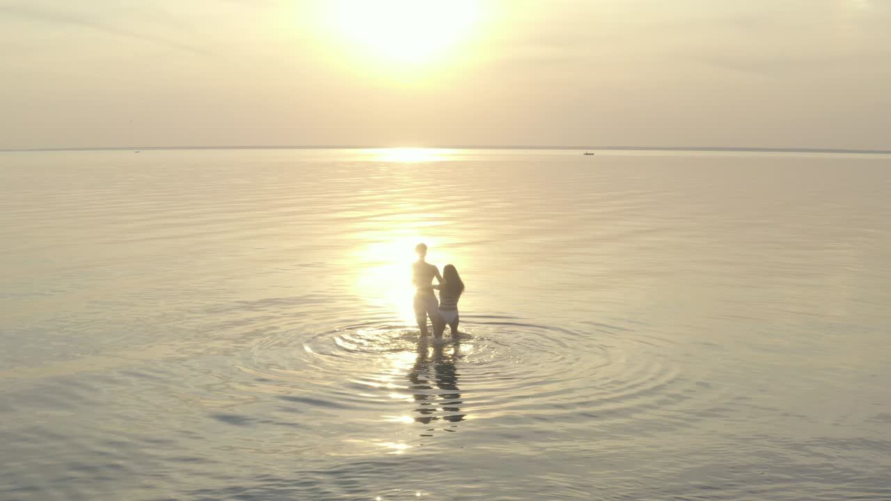 The young couple hold hands and spin in circle on the water