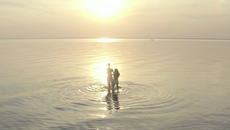 the young couple hold hands and spin in circle on the water