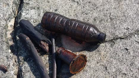 black oil covered marine debris, flotsam that washed up on the shore of lazarus island in singapore due to an oil spill