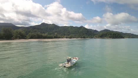 small fishing motor boat of the coast of thai tropical island with mountains, blue sky