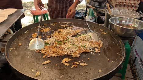 cooking a traditional thai oyster omelet on a hot pan.