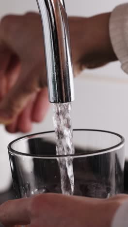 person filling glass with water