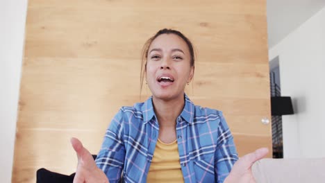 emotional biracial woman making video call talking and gesturing in living room, in slow motion