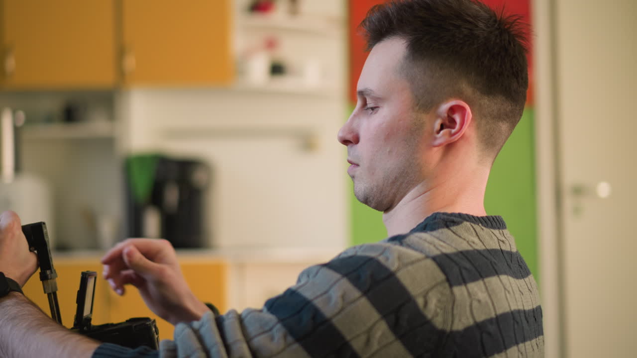 Man adjusting camera equipment, preparing for filming in creative home studio. Focused on handheld camera setup, with green walls and modern furniture in background, ready for content creation