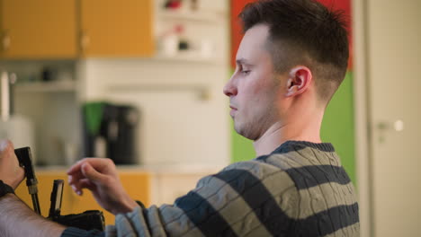 man adjusting camera equipment, preparing for filming in creative home studio. focused on handheld camera setup, with green walls and modern furniture in background, ready for content creation