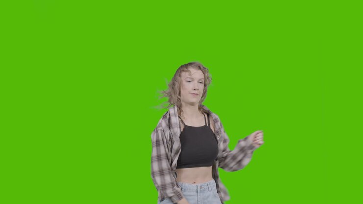 Studieoptagelse af ung kvinde, der har det sjovt med at danse mod grøn skærm 2