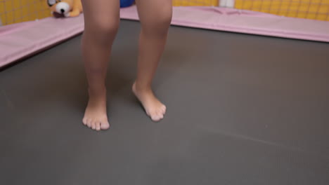 legs closeup of girl jumping barefoot on a small indoor trampoline at home