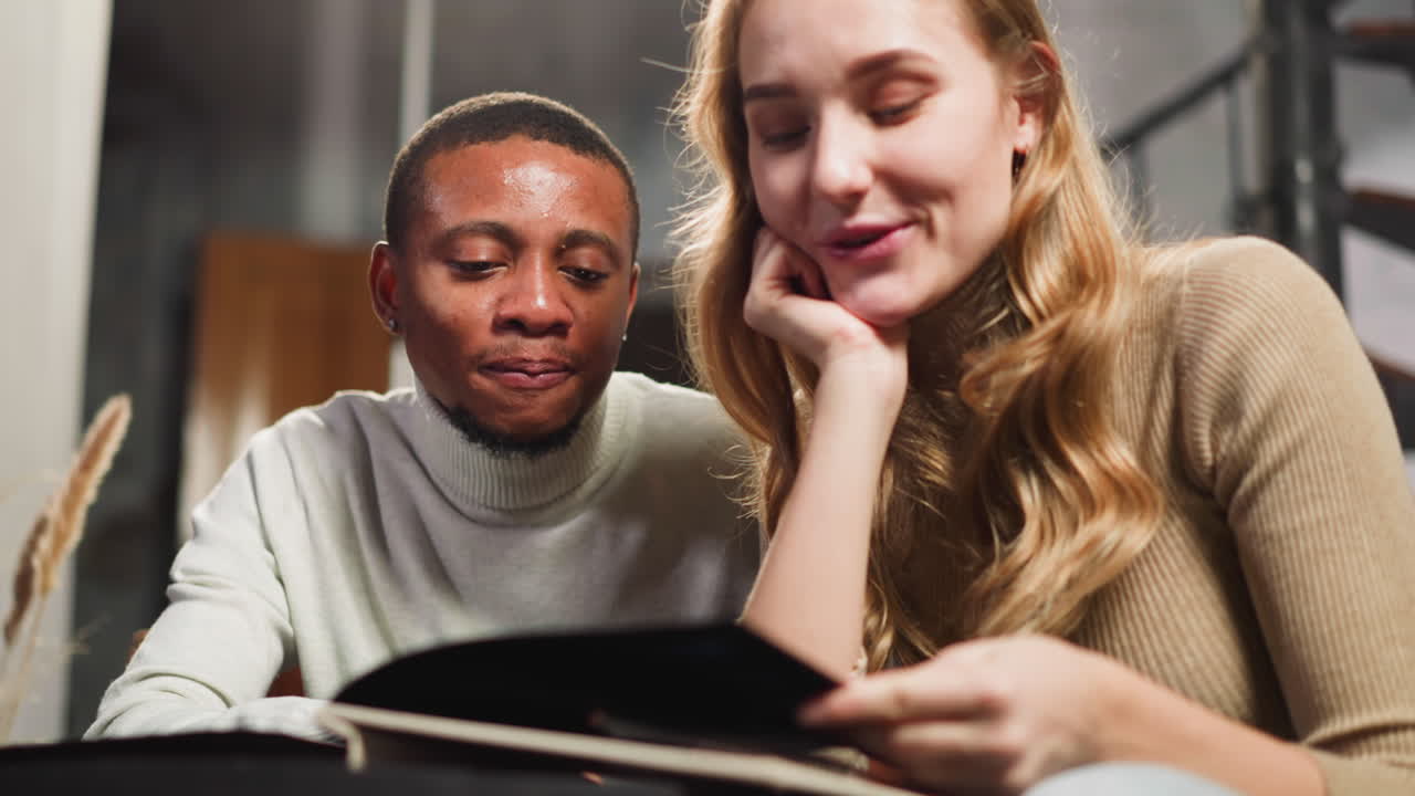 hombre barbudo afroamericano da vuelta a la página del álbum con una mujer