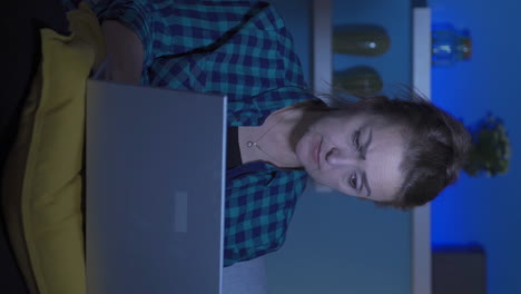 el video vertical de una mujer centrada en la computadora tiene una expresión seria. en casa por la noche.