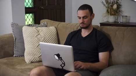 man sitting on couch using laptop at home
