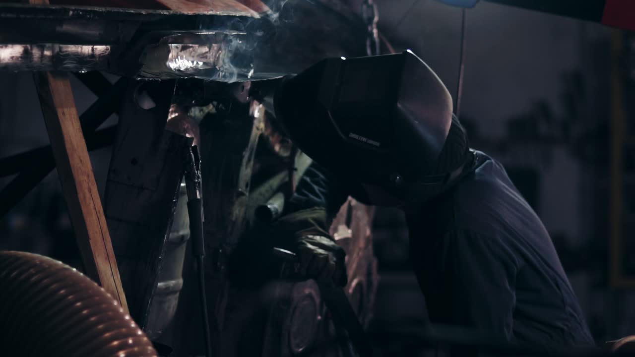 Male worker examines metal construction to adjust some piece of metal detail to it.