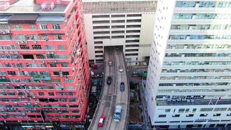 Traffic-passing-through-a-Car-park-building-in-downtown-Hong-Kong,-with-city-mega-buildings,-Aerial-view