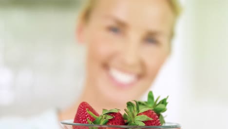 Portrait-of-smiling-woman-holding-a-bowl-of-strawberry