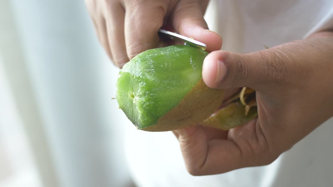 Peeling a kiwi fruit with a knife