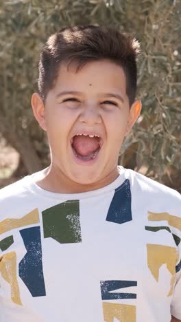 young boy smiling at the camera in the middle of a field
