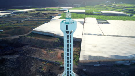 Aerial-view-in-orbit-over-the-Las-Hoyas-lighthouse-on-the-island-of-La-Palma,-near-banana-trees-and-the-coast