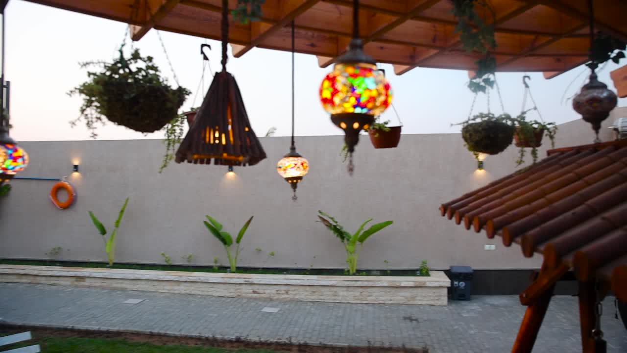 Gimbal, camera moving through beautiful light and plants decor hanging in backyard