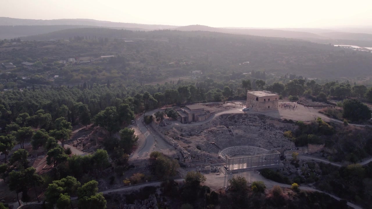 Vista aerea di un antico teatro romano e rovine in un paesaggio boscoso.